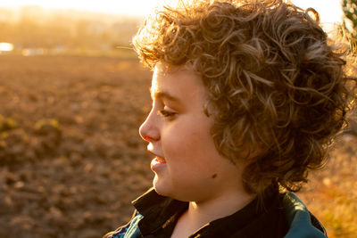 Side view of smiling boy looking away on land during sunset