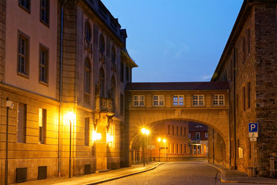 Empty road along buildings at night
