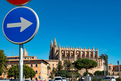 Low angle view of road sign against clear blue sky