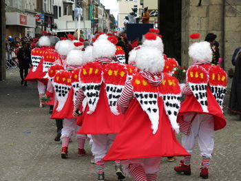 Rear view of people in costumes walking on street during carnival