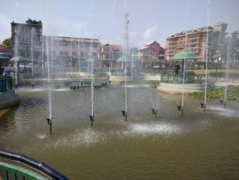 Fountain in city against sky