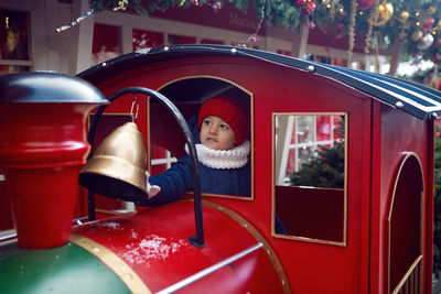 Child boy in a jacket sits in a toy train in moscow for the new year 2020 in winter