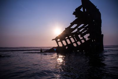 Silhouette people on beach against clear sky during sunset