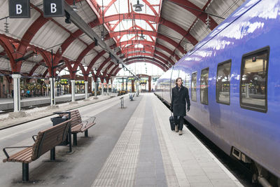 Man with suitcase walking along train at train station