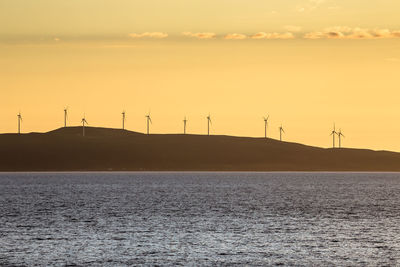 Scenic view of windmill field by the sea