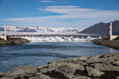 Bridge over river against snowcapped mountains