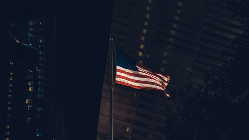 Low angle view of flag against buildings in city at night