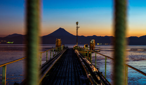 Pier over sea against sky during sunset