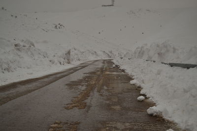 Road amidst snowcapped mountains against sky during winter