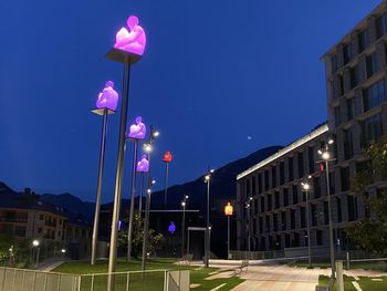 Low angle view of illuminated street light against building at night