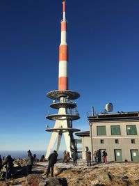 Low angle view of people against clear blue sky