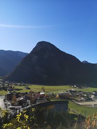 Townscape by mountains against clear blue sky