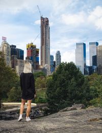 Rear view of woman standing by cityscape against sky