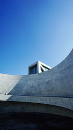 Man walking on spiral walkway against blue sky