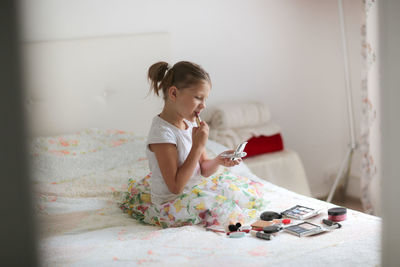 Kid girl in my mother's bedroom took out mother's make-up and lipstick, the concept of a childhood