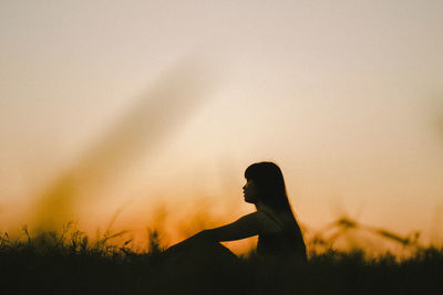 Side view of silhouette woman on field against sky during sunset