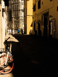 Bicycle on street amidst buildings in city at night