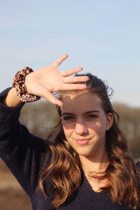 Portrait of smiling teenage girl shielding eyes during sunny day