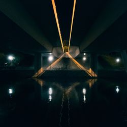 Illuminated lights hanging from ceiling in water at night