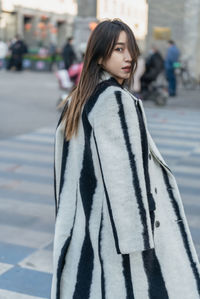 Portrait of young woman standing on street