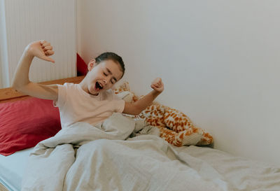 A little girl pulls herself up in bed in the morning.