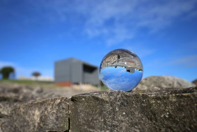 Close-up of blue ball on rock against sky