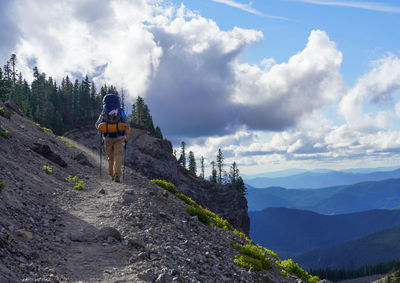 Rear view of man standing on mountain against sky