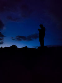 Silhouette man standing against blue sky at night