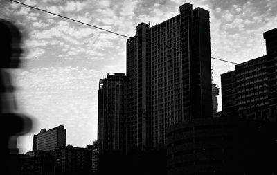 Low angle view of skyscrapers against cloudy sky