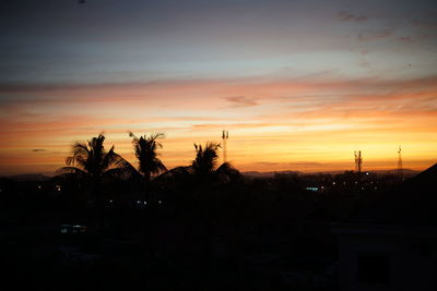 Silhouette trees and buildings against sky during sunset