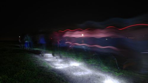 Illuminated road against sky at night