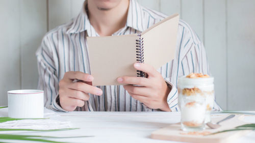 Midsection of woman holding coffee cup on table