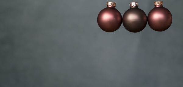 Close-up of baubles hanging against gray background