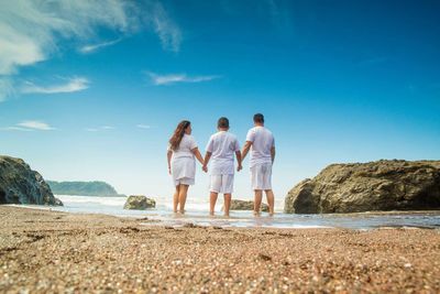 Rear view of people on beach against blue sky