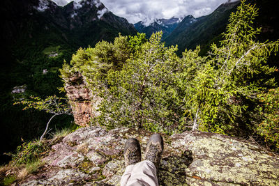 Low section of person on rock by mountains