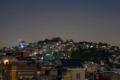 Illuminated cityscape against clear sky at night