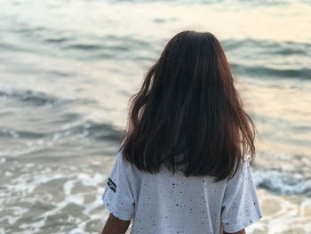 Rear view of woman standing at beach