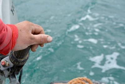 Cropped hand holding handle by sea