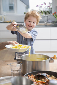 Proud little boy serving pasta in kitchen