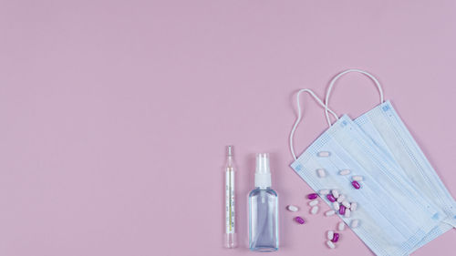 Close-up of pink water hanging from bottle against gray background