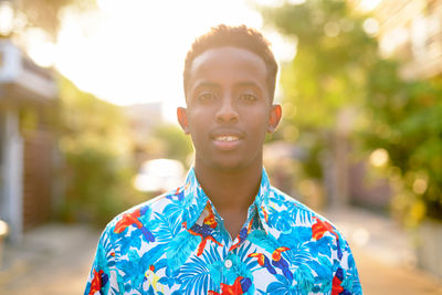 Portrait of young man standing against trees