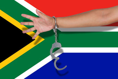 Cropped hand of person wearing handcuffs against south africa flag