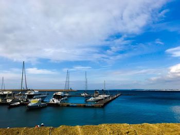 Sailboats moored on sea against sky