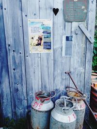 Milk canisters against wooden wall with posters