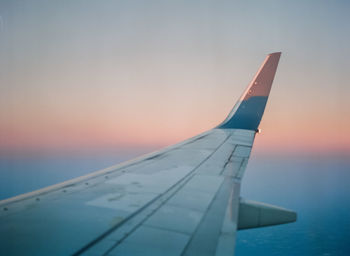 Close-up of airplane wing over sea against sky