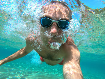 Funny guy having fun and taking underwater selfie while swimming in the sea