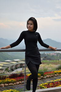 Young woman standing by railing on observation point against sky