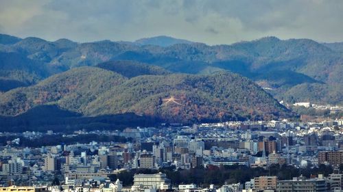 Aerial view of cityscape and mountains against sky