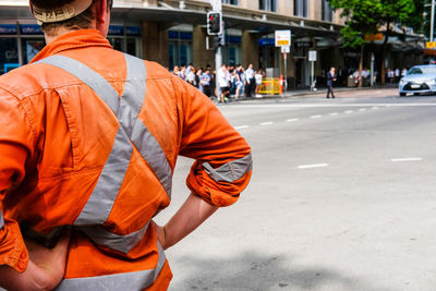 Rear view of man in protective workwear while standing on road