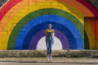 Young transgender person levitating in front of rainbow wall